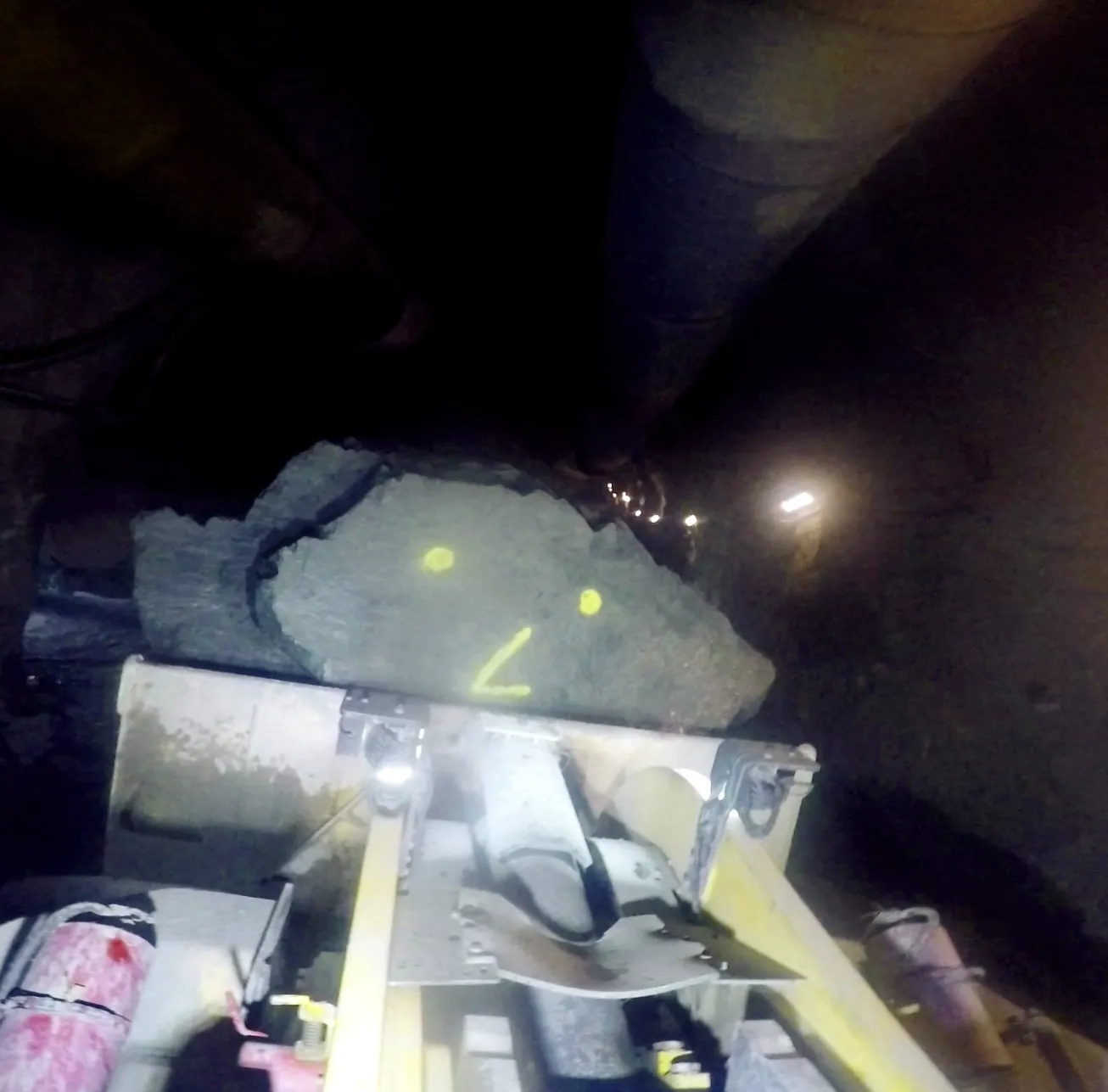 A slab of rock with a painted smiley face on a machine deck.